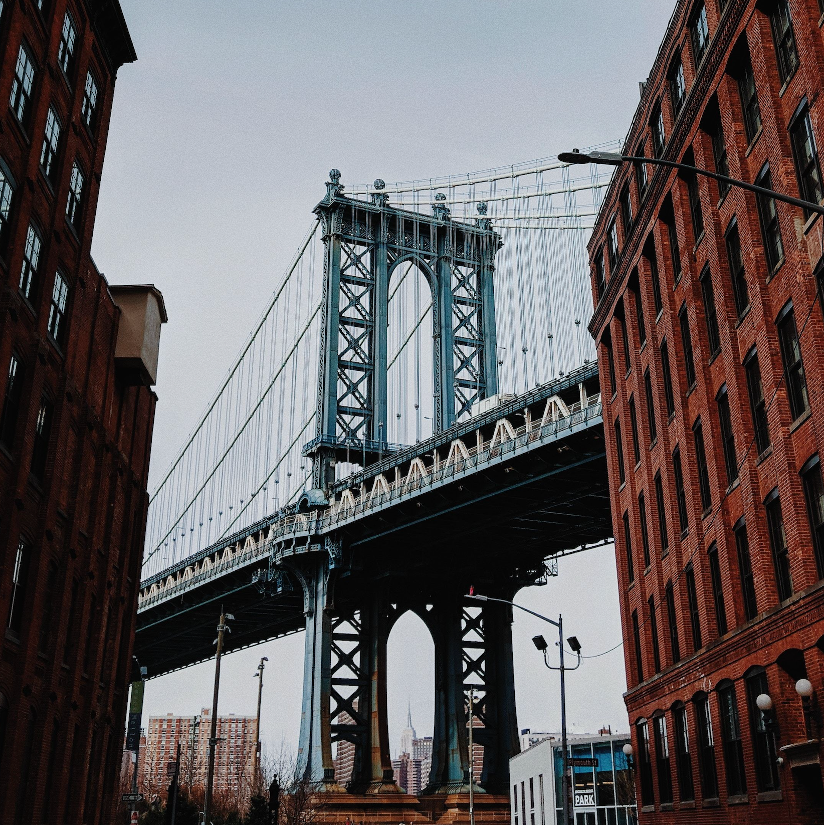 The Brooklyn Bridge towering over brick buildings in Williamsburg