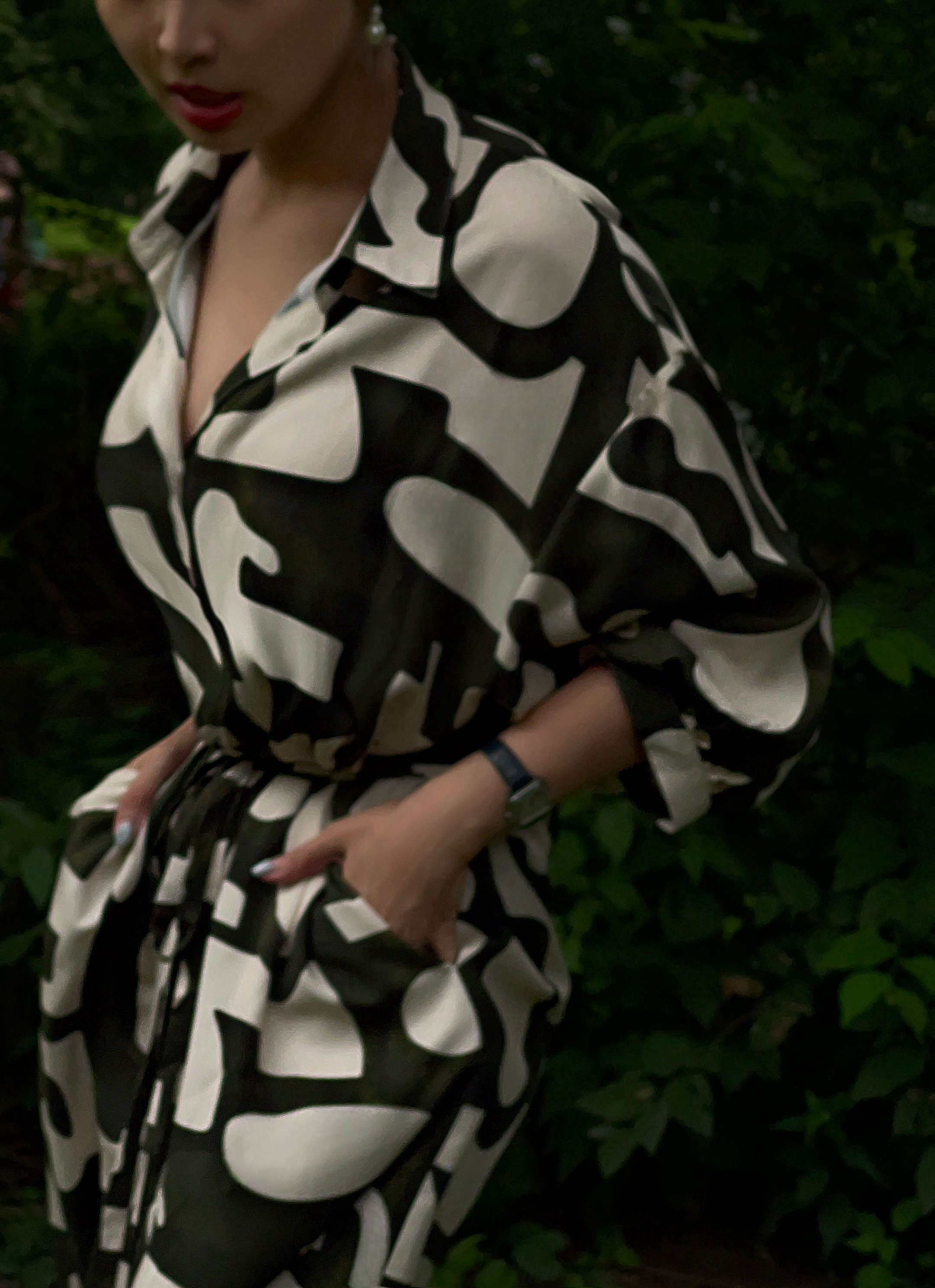 model posing in a green printed puff sleeve shirt dress against a lush green background