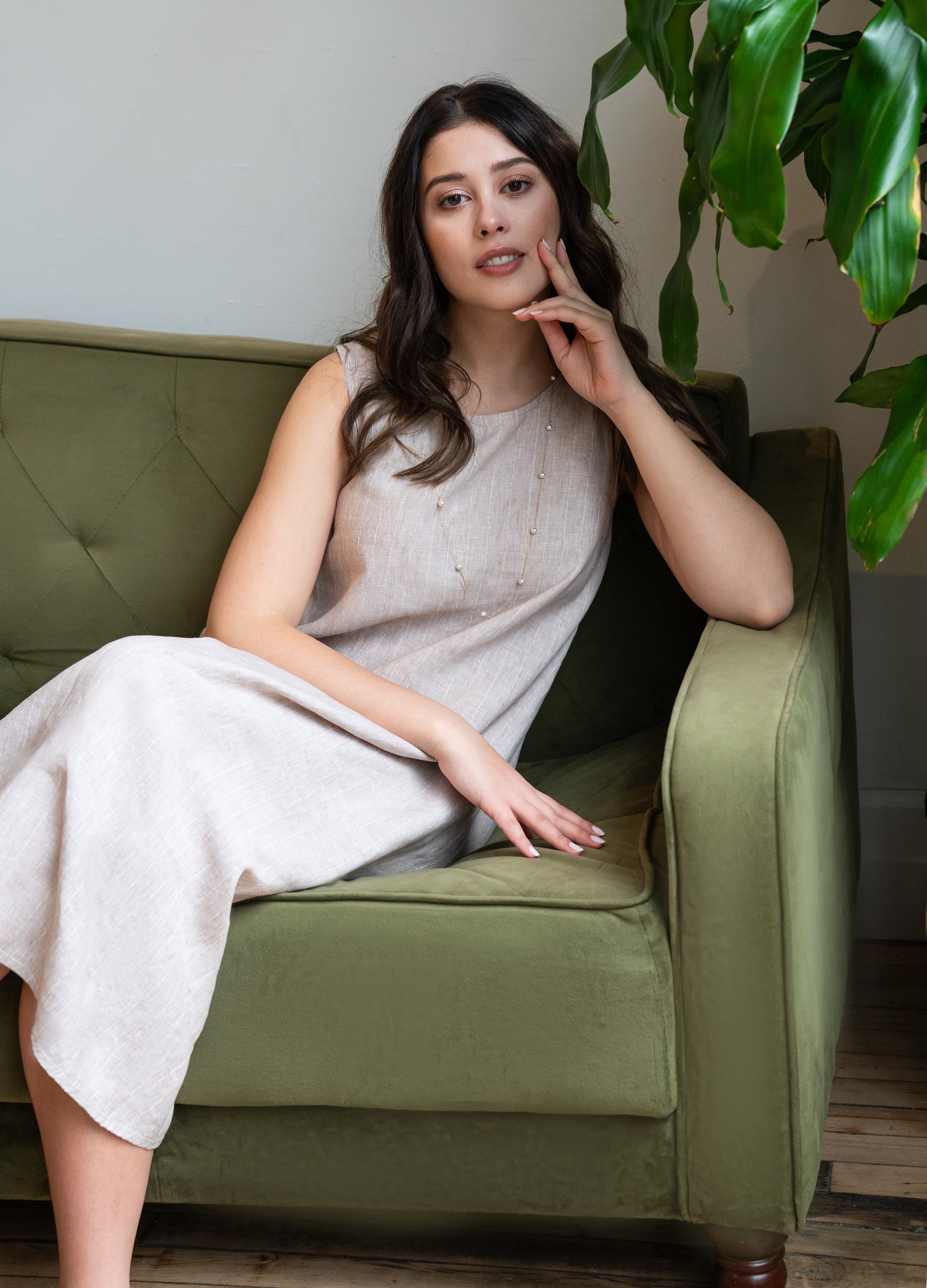 model posing on a couch in a beige sleeveless midi dress