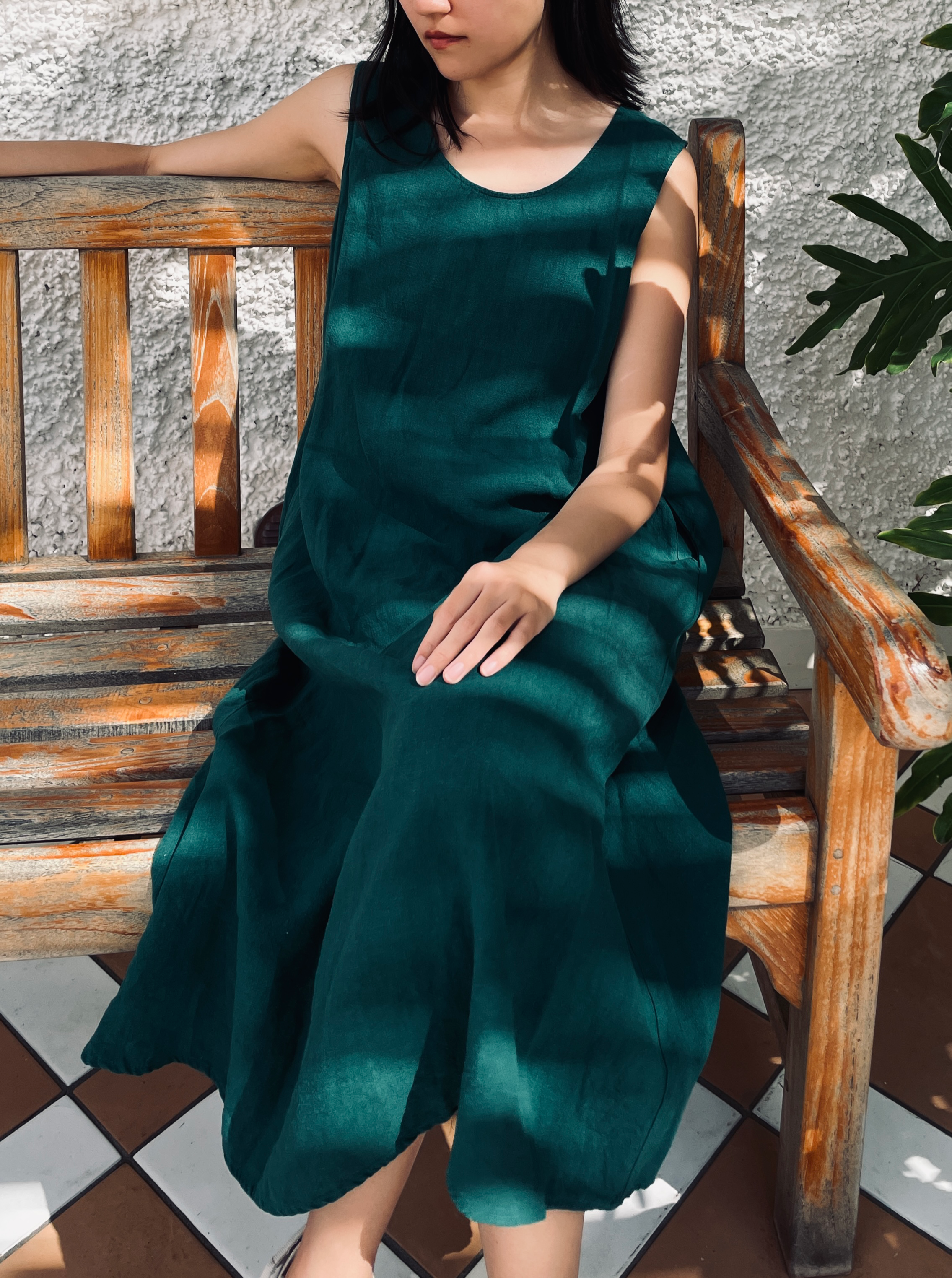 model posing in an emerald sleeveless midi dress
