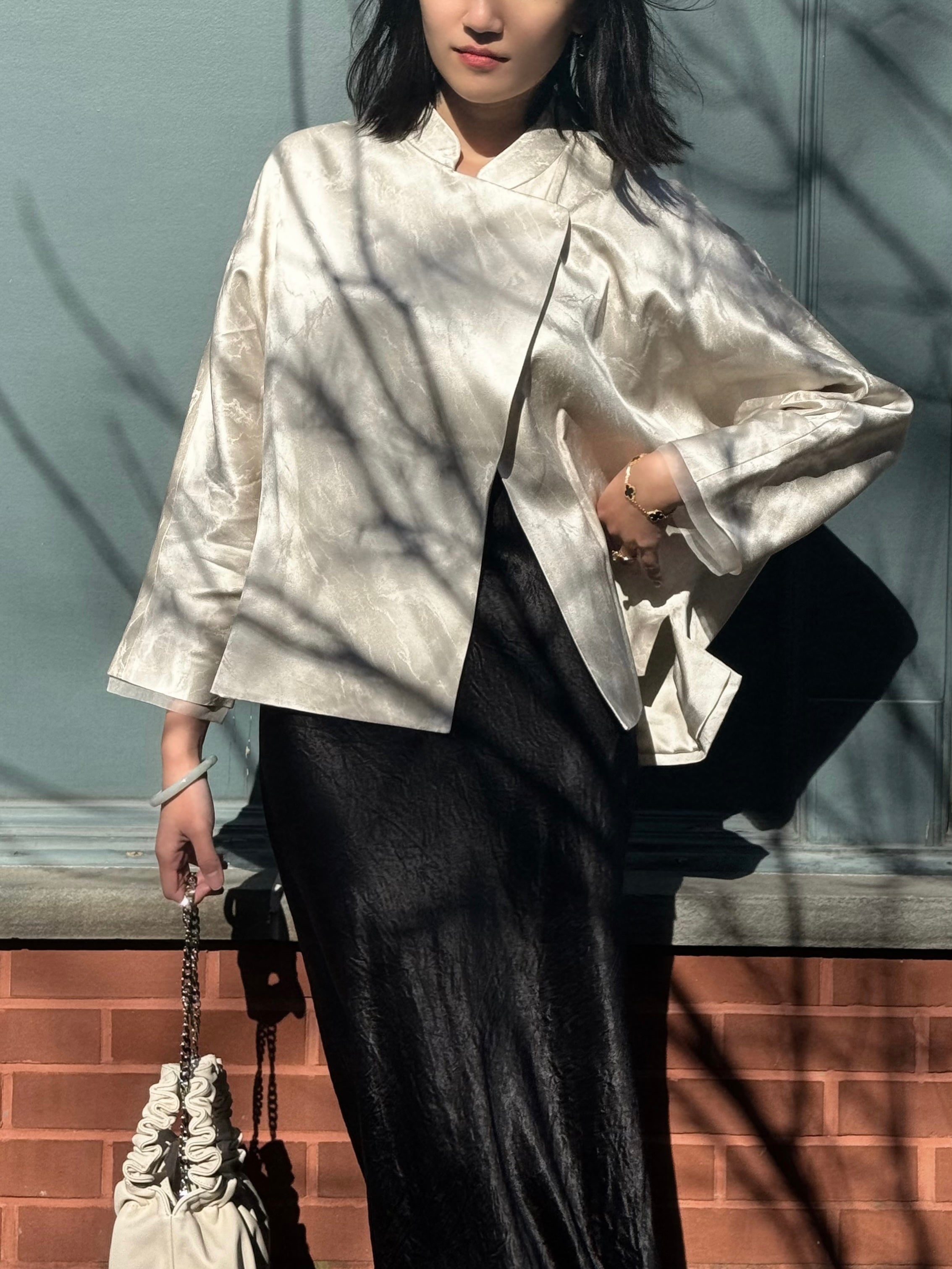 model posing in white silk jacket and black wide strap slip dress
